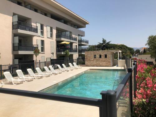 een zwembad met stoelen en een gebouw bij Spacieux appartement avec jardin dans résidence de grand standing avec piscine in Sanary-sur-Mer
