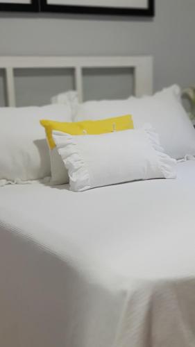 コルドバにあるCentro Córdobaの白い枕と黄色い枕が付いた白いベッド