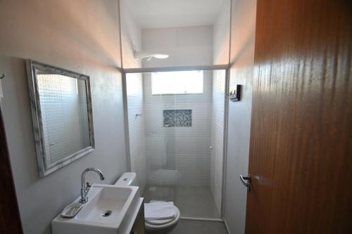 La salle de bains est pourvue de toilettes, d'un lavabo et d'une douche. dans l'établissement Pousada Barra Sul, à Laguna