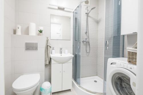 a white bathroom with a toilet sink and a washing machine at Apartament uJasia in Słupsk