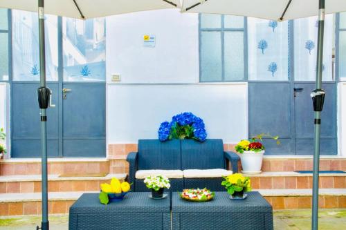 a blue chair and a table with flowers and an umbrella at Penisola Home Experience in Vico Equense