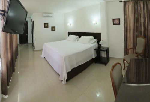 a bedroom with a white bed and a flat screen tv at Hotel Estrella Palmira in Palmira
