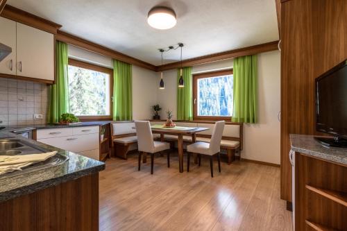 una cucina con tende verdi e tavolo e sedie di Ciasa MAEL Dolomites Apartments a La Valle