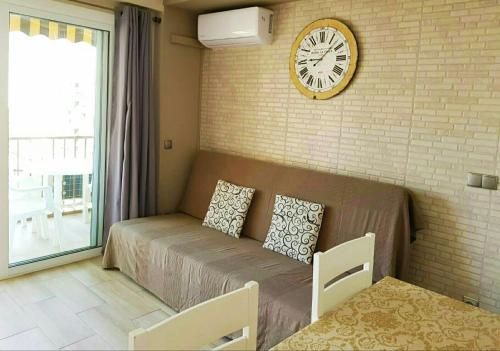 ein Wohnzimmer mit einem Sofa und einer Uhr an der Wand in der Unterkunft Apartamento Benidorm Luxury Levante in Benidorm