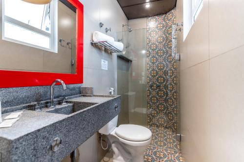 a bathroom with a toilet and a sink and a mirror at Hotel Monte Castelo in Rio de Janeiro