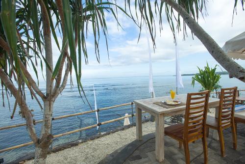a table and chairs with a view of the ocean at Twilight Ceningan in Nusa Lembongan