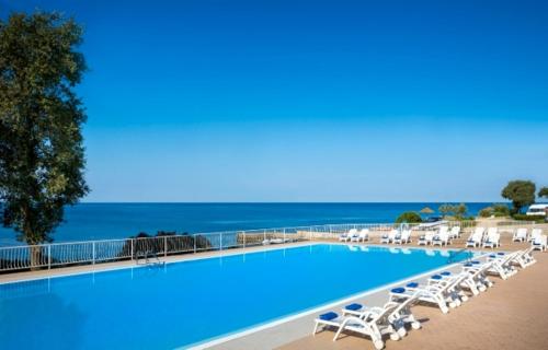 a large swimming pool with lounge chairs and the ocean at West Coast Mobilhome with XXL Terrace in Naturist Resort Solaris FKK in Poreč