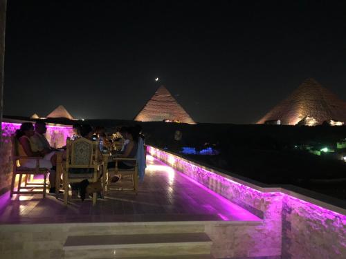 a group of people sitting on a deck at night with the pyramids at Great Pyramid Inn in Cairo