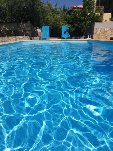 a swimming pool with blue chairs in the water at Holiday home with pool, Supetar, Island Brac in Supetar