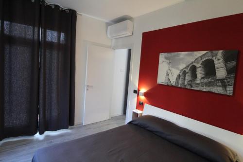 a bedroom with a red headboard and a red wall at Villa Lori Apartments Garden and Beach in Peschiera del Garda