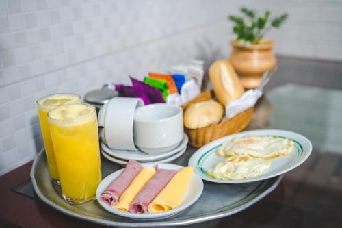 a tray with plates of food and drinks on a table at Hotel Avenida in São João de Meriti