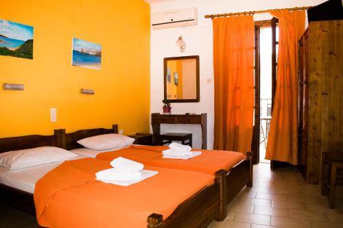 two beds in a room with yellow walls at Eleni's House Skiathos in Skiathos