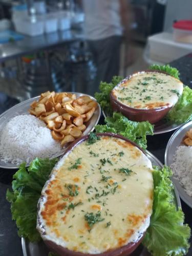 a table topped with plates of food with cheese at Hotel Costa Norte Massaguaçu in Caraguatatuba
