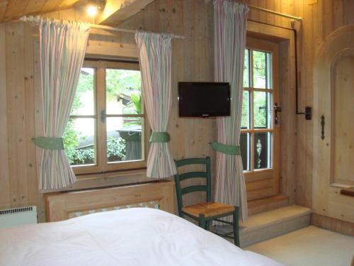 a bedroom with a bed and a tv and windows at Weberhaus - Adults Only in Kitzbühel