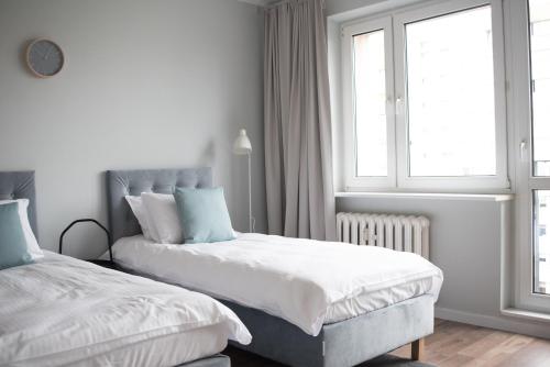 een witte slaapkamer met 2 bedden en een raam bij TS Budget Stay in Szczecin