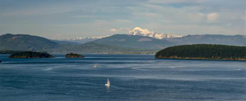 a sail boat in a large body of water with mountains at Sunrise Inn in Anacortes