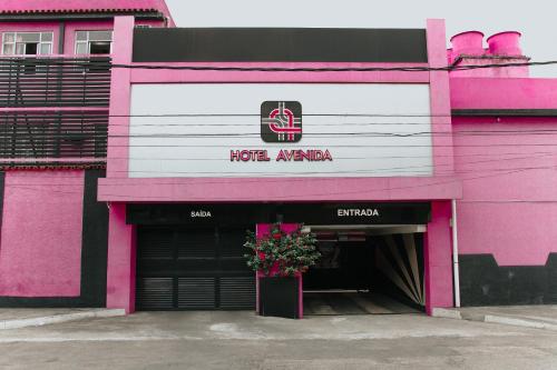 a pink and white building with a flower pot in the doorway at Hotel Avenida in São João de Meriti