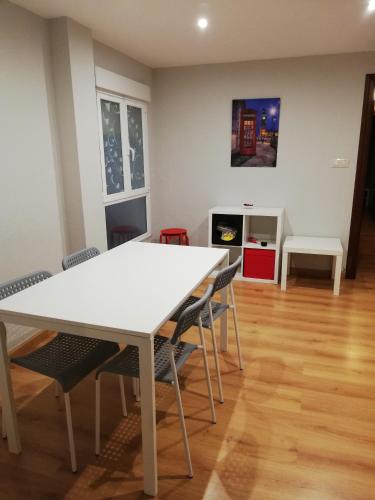a dining room with a white table and chairs at Alojamiento Quintanilla in Gijón