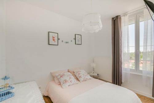 a white bedroom with a bed and a window at Maison Qui s'y frotte s'y pique in Robert-Espagne