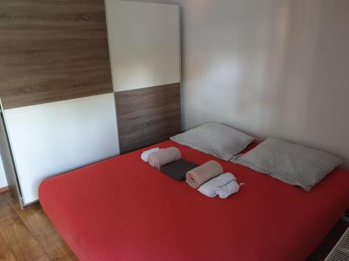 a room with a red bed with two pillows at Apartman Max 2 in Biškupec Zelinski