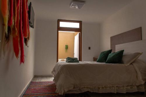 a bedroom with a bed with green pillows and a window at Hotel Boutique Suri in La Serena