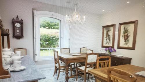 a dining room with a table and chairs and a clock at Villa Marta Casa de Indianos Passive House in Villanueva de Ardisana