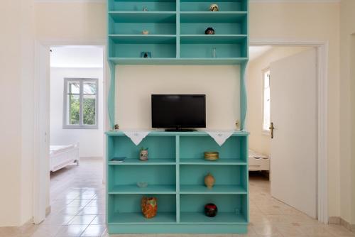 a blue book shelf with a television in a room at Eftihias house in Kefallonia