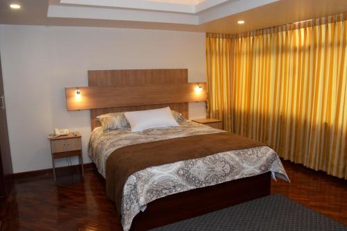 a bedroom with a large bed and a yellow curtain at Los Angeles Stay Inn in Quito