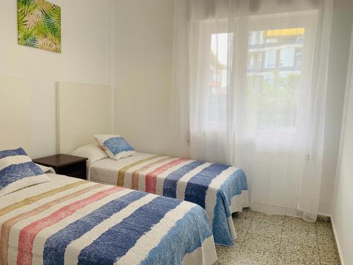 a bedroom with two beds and a window at Casa con Jardín con 2 alojamientos, con jardines no compartidos y aparcamiento privado in Noja