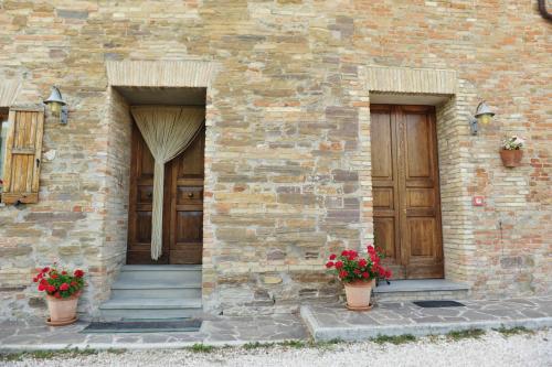 two entrances to a brick building with wooden doors and flowers at Agriturismo La Caputa in Urbania