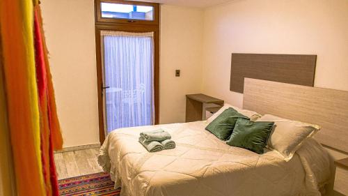 a bedroom with a bed with green pillows and a window at Hotel Boutique Suri in La Serena