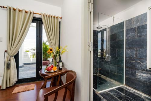 a bathroom with a glass shower and a table with a bowl of fruit at Blue An Bang Villa in Hoi An