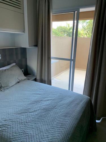 a bedroom with a bed and a large window at Flat Granja Viana in Cotia