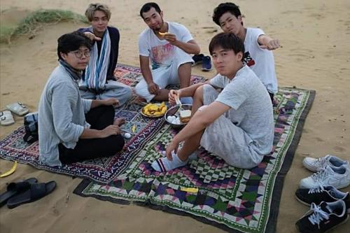 a group of young men sitting on a blanket on the beach at Mirvana Guest House & Camel safari in Jaisalmer