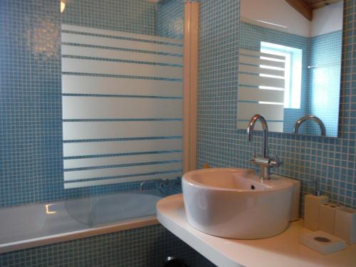 La salle de bains est pourvue de carrelage bleu, d'un lavabo et d'une baignoire. dans l'établissement Quinta Da Ribeira Da Urze, à Prainha de Cima