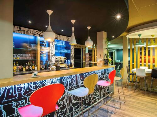 a bar with colorful bar stools in a restaurant at ibis Tarbes Odos in Odos