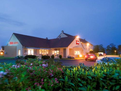 a building with a car parked in a parking lot at ibis Falaise Coeur de Normandie in Falaise