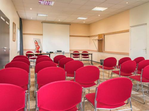 an empty room with red chairs and a chalkboard at ibis Falaise Coeur de Normandie in Falaise