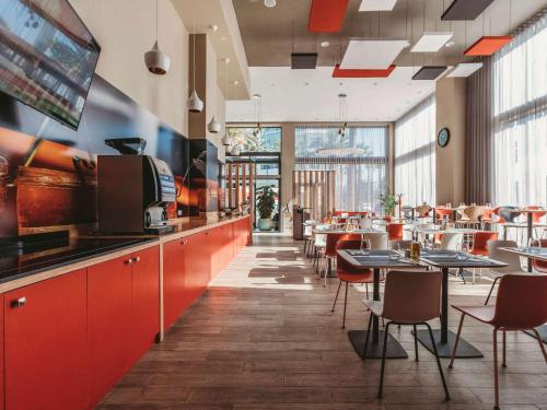 a restaurant with red cabinets and tables and chairs at Ibis Mohammedia in Mohammedia