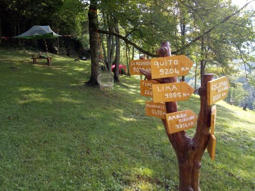 a wooden sign with signs on it in the grass at D'tente sky lodge in Massat