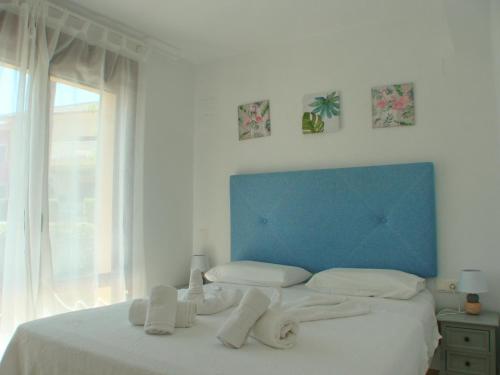 ein Schlafzimmer mit blauem Kopfteil und weißem Bett in der Unterkunft Jardines de Montemar in Benissa