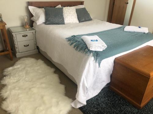 um quarto com uma cama branca e um tapete branco em Southland Organic Farmstay em Invercargill