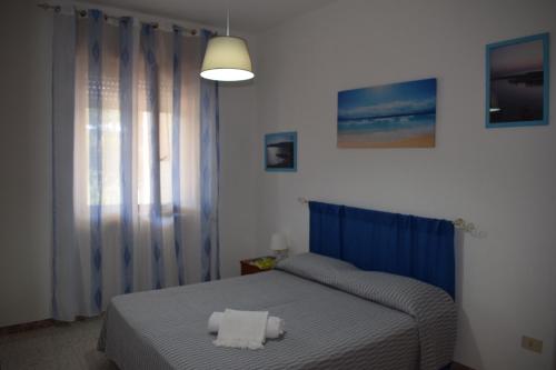 マリーナ・ディ・マンカヴェルサにあるAlba Chiara - Villa con Giardinoのベッドルーム1室(ブルーベッド1台、タオル2枚付)