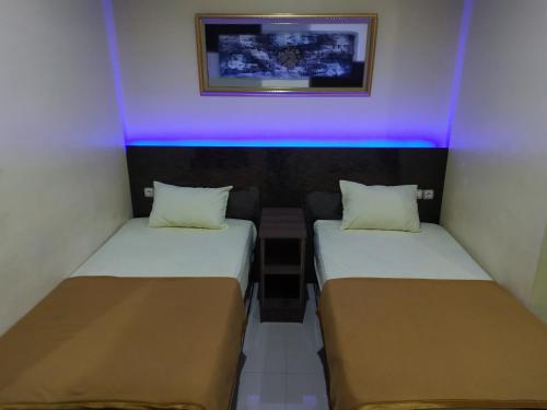 two beds in a small room with purple lights at Hotel Grand Royal in Paklintingan