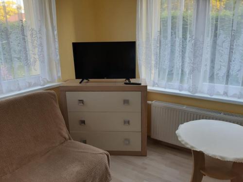 a living room with a tv and a chair and windows at Apartament u Basi in Gdańsk