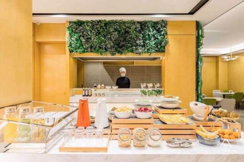 a woman is standing behind a counter with food at Atour Hotel Yangzhou Ancient Canal Dongguan Street in Yangzhou