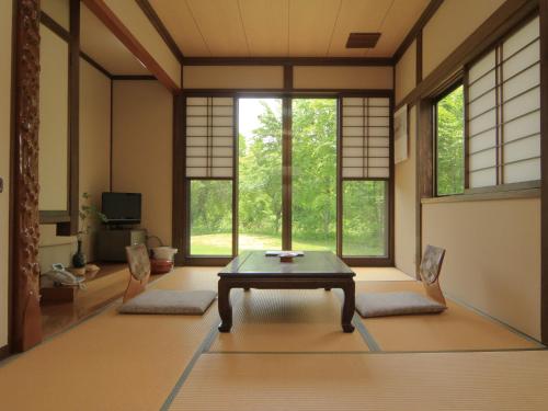 a room with a table and two chairs and windows at Bunanoyado Koase in Aga