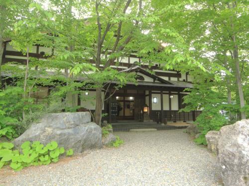 a building with trees and rocks in front of it at Bunanoyado Koase in Aga