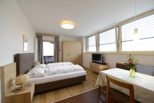 a bedroom with a bed and a table and a tv at Residence Badleit in Lagundo