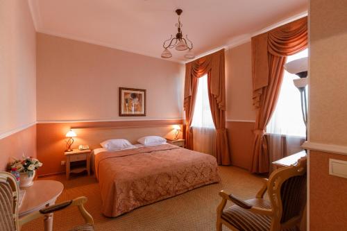 ein Hotelzimmer mit einem Bett und zwei Fenstern in der Unterkunft Hermitage Hotel Rostov-on-Don in Rostow am Don